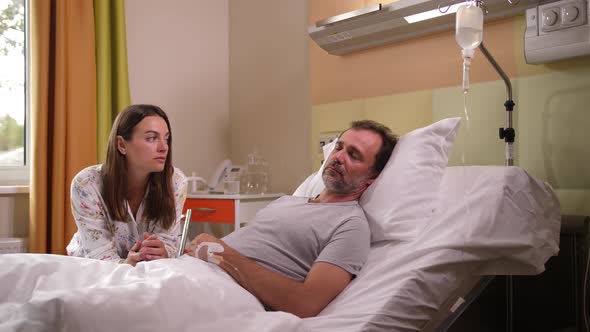 Sad Woman Crying at Sick Husband's Bedside in Ward