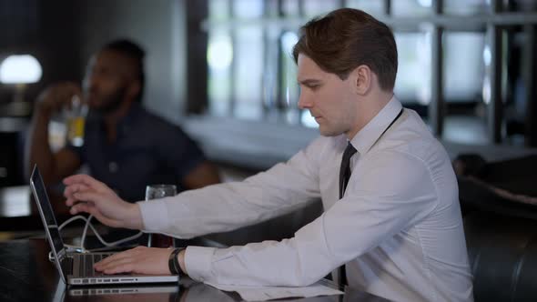 Young Man Messaging Online Closing Laptop As Unrecognizable Waiter Bringing Beer Snack