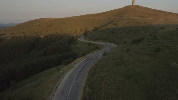 Drone Following Energetic Cyclist Speeding Down Asphalt Mountain Road at Sunset