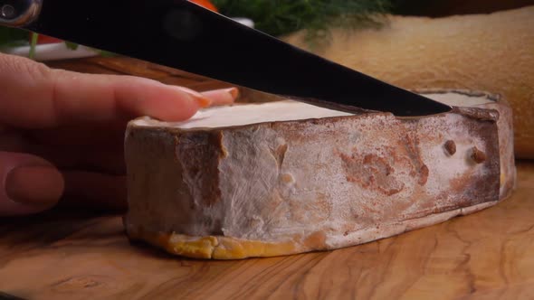 Knife Cuts Creamy Epoisses Cheese in Brown Mold