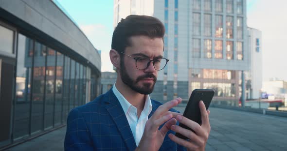 Happy Amazed Businessman Looking at Smartphone and Saying WOW