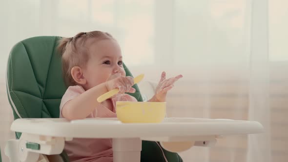 Funny Kid Eats and Laughs While Sitting at a Table at Home