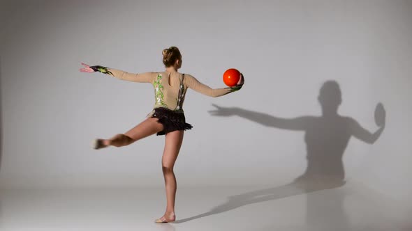 Gymnast with the Ball in His Hands Doing Acrobatic Moves. White Background