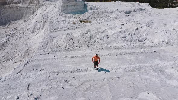 Shirtless athlete on white mountain. Active sportsman on white natural rocky background.