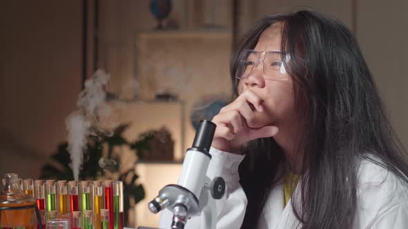 Young Scientist Girl With Dirty Face Looking At Microscope And Thinking In Laboratory