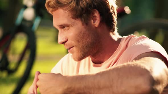 A close-up view of a blonde man is talking to his son while having a picnic on the grass