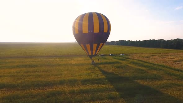 People Walking Around Wicker Basket of Air Balloon Landed in Field Destination