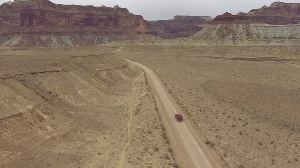 Aerial view following truck driving on dirt road through the Utah desert