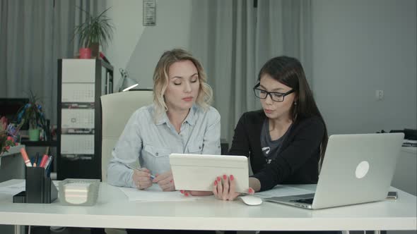 Two Female Professionals Using Digital Tablet While Working at the Desk