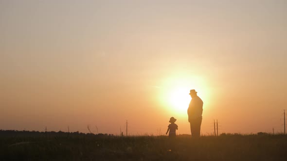 Two Generations Silhouette of a Mature Grandfather and Little Grandson Play at Sunset.