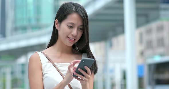 Asian Woman look at the smart phone in city