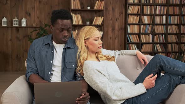 Happy Mixed Race Couple Spends Leisure Time Online with a Smartphone