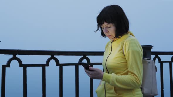 Traveler Woman in Foggy City Uses Smartphone for Navigation