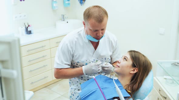 Young girl at the dentists appointment. Male doctor in medical gloves gives recommendations