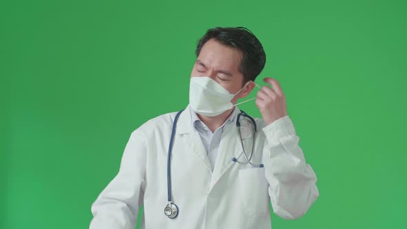 Tried Asian Doctor Removing The Mask While Standing In Front Green Screen