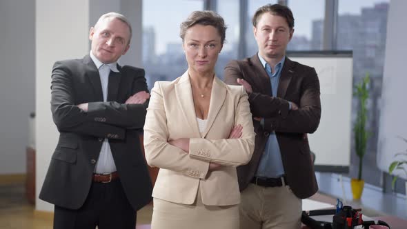 Three Confident Successful Office Workers Crossing Hands Looking at Camera with Confident Facial