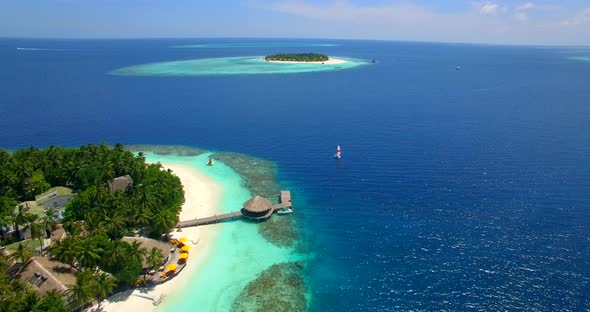 Aerial drone view of a man and woman sailing on a boat to a tropical island