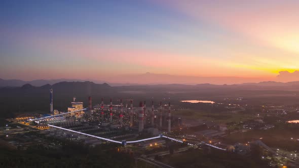 Aerial view over coal-fired power plant at sun dawn with smoke from cooling,