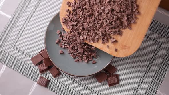 Woman Pouring Chopped Black Dark Chocolate From Wooden Cutting Board to Plate