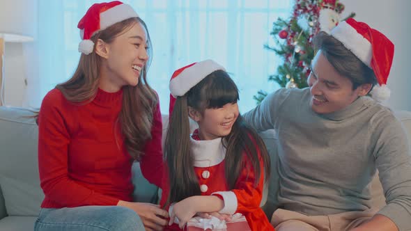 Portrait of Asian happy family wear Santa hat, sitting in living room.