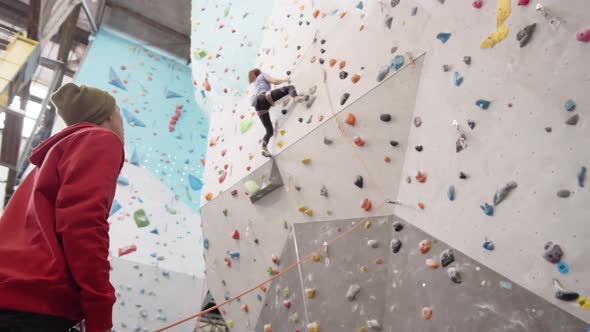 Coach Watching Sporty Woman Practicing Climbing