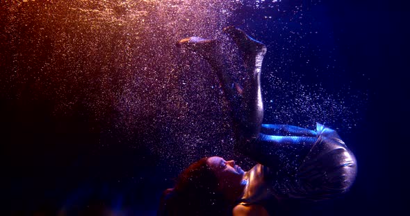 Close-up of a Dark-haired Middle-aged Woman Doing a Somersault in a Studio Under Water and Floating