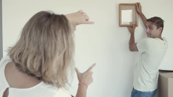 Family Couple and Kid Hanging Picture Frame on Wall