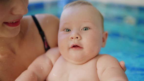 Happy Mother in Red Swimming Suit with Baby Son Surfing Water with Fun in Swimming Pool