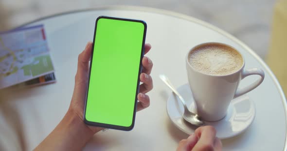Crop View of Female Person Holding Smartphone and Pressing on Mockup Screen While Sitting at Table