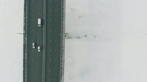 Automobiles Drive Along Large Grey Bridge Over Frozen River