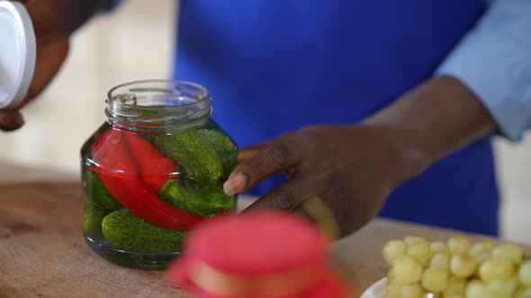 Closeup Unrecognizable African American Man in Apron Screwing Cap on Bottle with Marinated