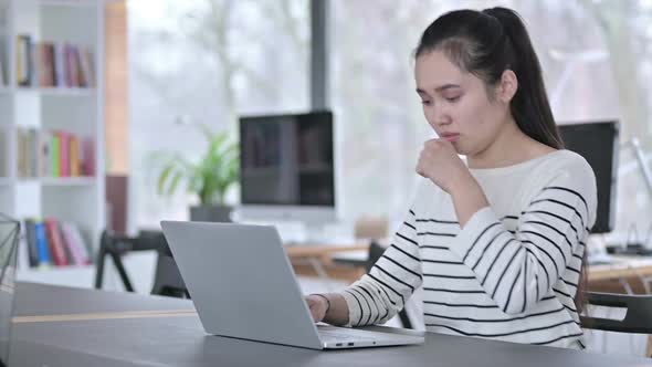 Coughing Young Asian Woman Using Laptop in Caf�