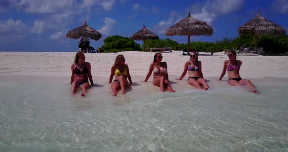 Modern smiling ladies on vacation having fun at the beach on summer white sandy and blue 4K backgrou