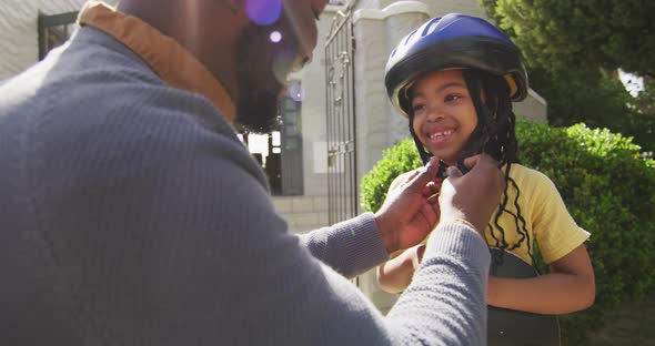 Happy african american father giving high five to daughter holding skateboard