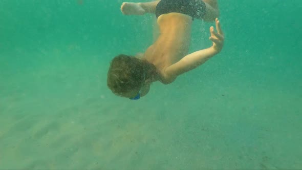 Superslowmotion Shot of a Little Boy Diving in the Blue Sea and Reaching the Bottom