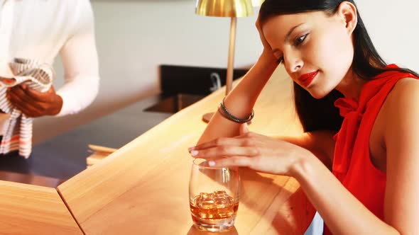 Tensed woman having a glass of whisky at counter