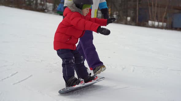 Young Man Snowboard Instructor Tiches Little Boy How To Ride a Snowboard, Winter Activities Concept