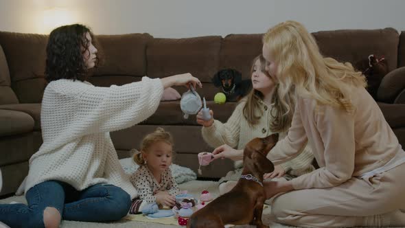 Young Mother Playing with Daughters and Pets While Sitting on Floor at Home Interior Rbbro