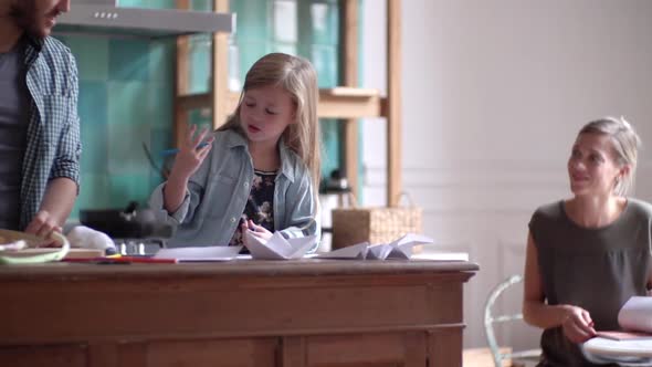 Family together in kitchen, father helping daughter with homework