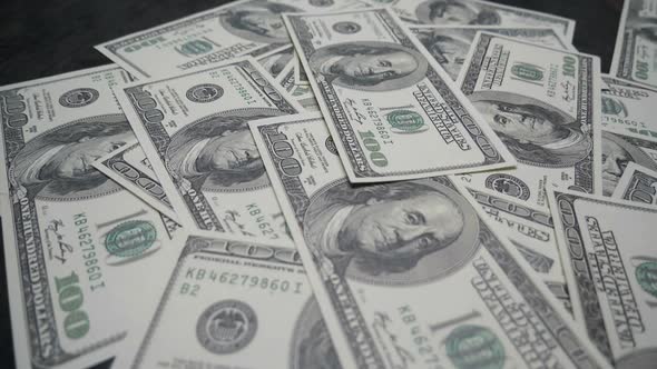 Hand of man placing dollar sheet on pile of banknotes.