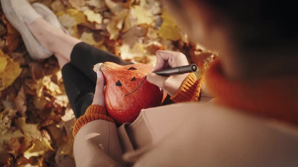 Preparation for Halloween African American Woman Hands Paint Orange Pumpkin with Black Paint