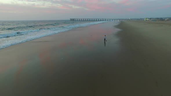 Aerial shot of little boy playing soccer on the beach at sunset