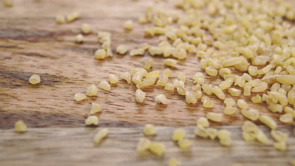 Yellow raw bulgur grains on a rustic wooden surface. Macro