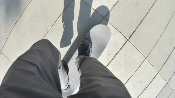 POV of a young man riding his skateboard in a town square.