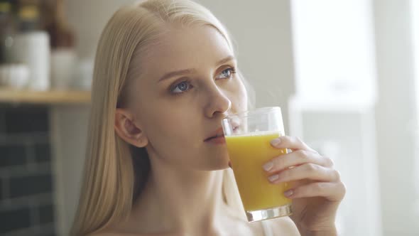 Pretty Woman Drinks Juice and Smiles at Camera on the Kitchen