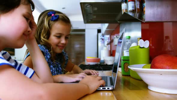 Siblings using laptop in kitchen