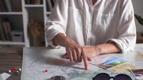A Young Girl Is Planning A Honeymoon Vacation Trip With A Map. Map View. The Index Finger Shows