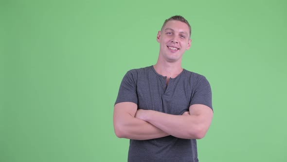 Portrait of Happy Young Man Smiling with Arms Crossed