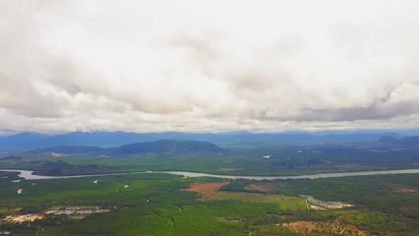 Drone view of a valley with a river and mountains in the background on a cloudy day