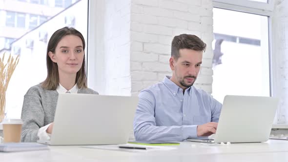 Attractive Creative Team Working on Laptop and Smiling at the Camera